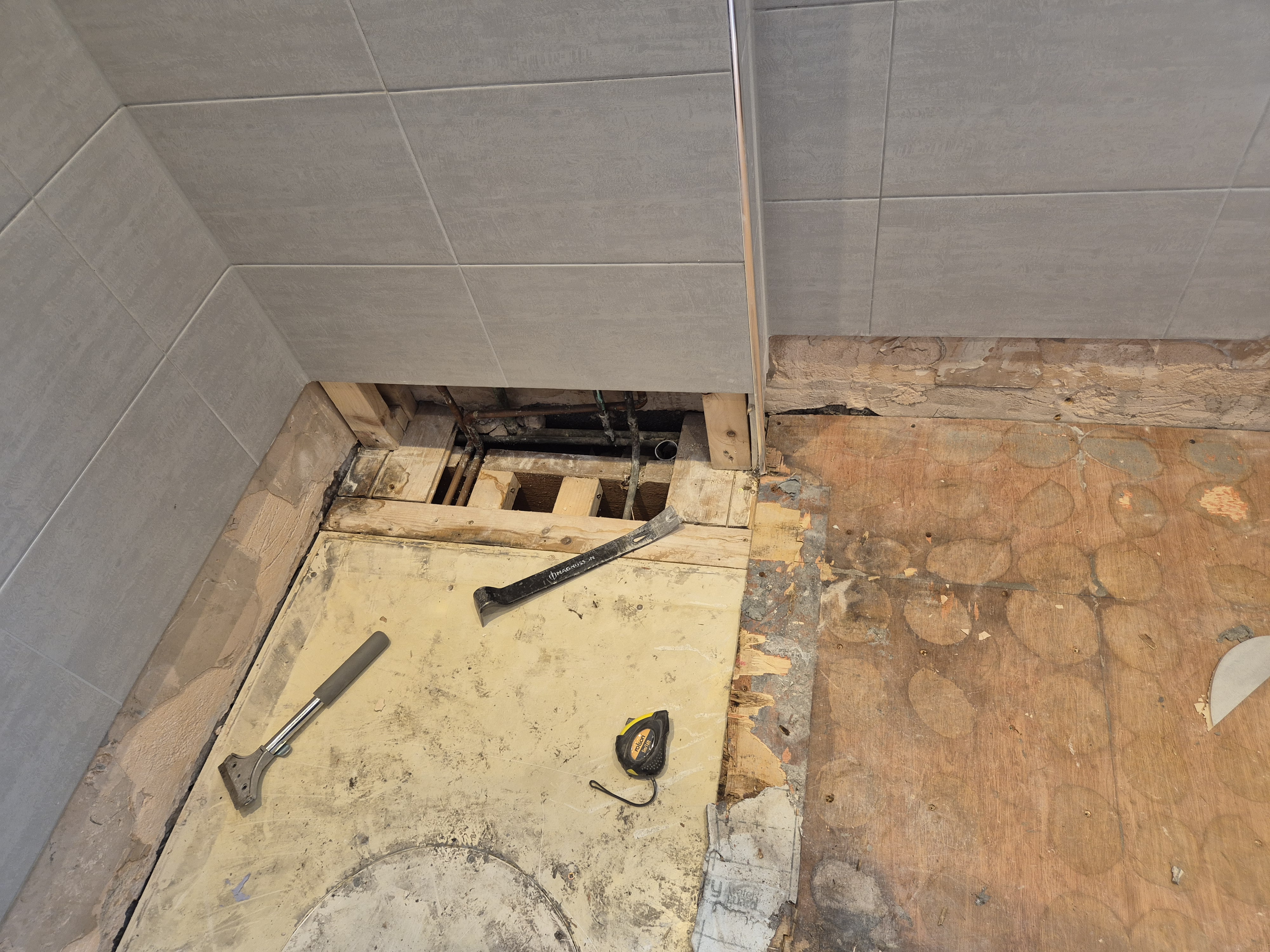 Floor opened up to reveal the timber joists and pipework below